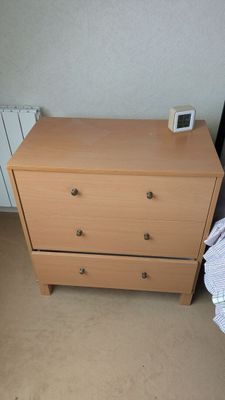 une commode sur laquelle est posée une horloge, dans une chambre à coucher