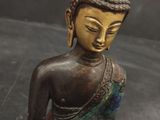 statue of a seated buddha holding a bowl of food on a black surface
