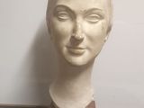 a white marble head of a woman on a wooden stand