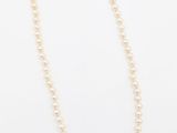 un collier de perles blanches avec un fermoir en or sur fond blanc