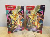 deux boîtes de cartes à collectionner Pokémon posées sur une table en bois