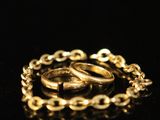 a close up of a gold chain bracelet on a black surface