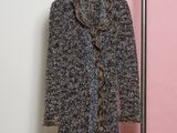 un manteau gris et noir suspendu à un portant devant un mur rose