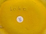 a close up of a yellow vase with a blue sticker on it