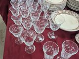 many glasses and plates on a table with a red table cloth