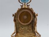 a gold clock with a blue vase on top of it