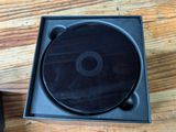 a black cd in a black box on a wooden table