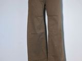 un pantalon marron posé sur un mannequin, devant un mur blanc
