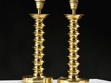 a pair of brass candlesticks on a white table