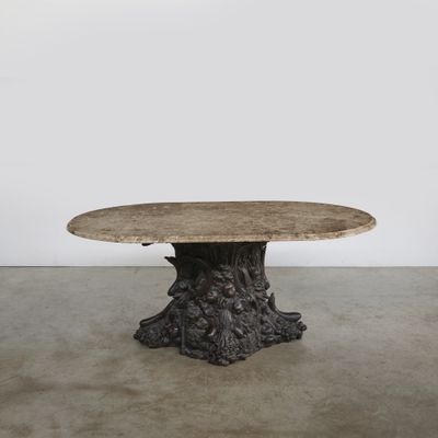 une table ronde avec un plateau en bois et un piètement sculpté