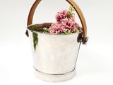 silver ice bucket with pink flowers in it on a white background