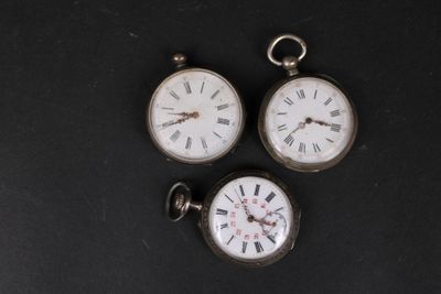 trois montres de poche anciennes posées sur une surface noire, avec des chiffres romains