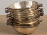 a stack of silver bowls with spoons on a table