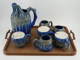 a tray with a pitcher, cups, and tea set on it