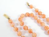peach colored beaded necklace with gold tone clasp on white background