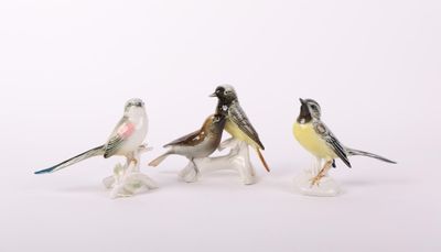 trois petites figurines d'oiseaux posées sur une surface blanche