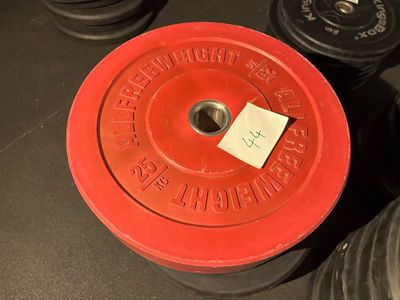 une plaque de poids rouge et noire sur laquelle est collé un autocollant