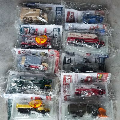beaucoup de petits camions en plastique dans des sacs en plastique, par terre