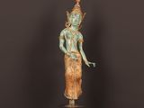 une statue en bronze représentant une personne debout sur une table en bois