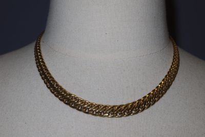 a close up of a gold chain necklace on a mannequin