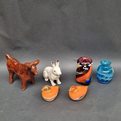 trois petites figurines d'animaux et un chat sur une surface grise