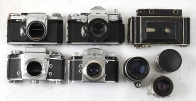 Plusieurs anciens appareils photo sont alignés les uns à côté des autres sur une surface blanche