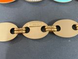 three different colored metal bracelets with a gold clasp and a blue, orange, and yellow clasp