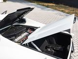 a white sports car with its hood open on the street