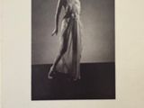 an old photo of a woman in a white dress holding a baseball bat