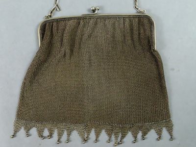 un vieux sac à main muni d'une anse en chaîne et orné de franges