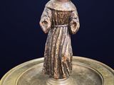 bronze figurine of a monk on a brass plate on a black background