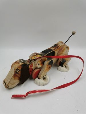 an image of a wooden toy dog with a red leash on a white surface