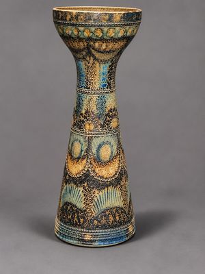 une image représentant un vase bleu et jaune posé sur une surface grise