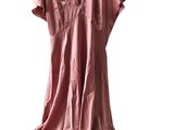 La robe rose est suspendue à un cintre sur un fond blanc.