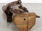 carved wooden sculpture of a man laying down on a wooden block