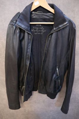 une veste en cuir noir suspendue à un cintre accroché au mur