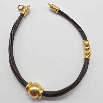 un gros plan d'un bracelet noir et doré posé sur une surface blanche