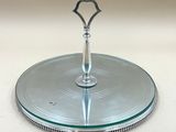 un plat à gâteau en argent surmonté d'un plateau en verre