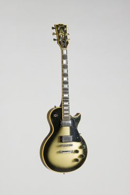 une guitare électrique suspendue à une corde sur un mur blanc