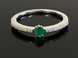 an image of a diamond and emerald ring on a black surface