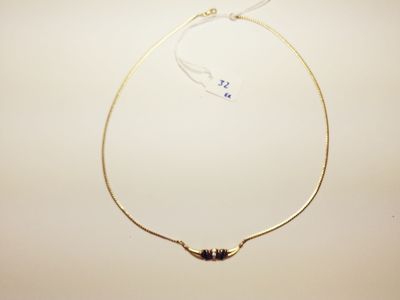 a close up of a gold necklace with a black bead on it