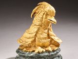 gold sculpture of a bird on a green marble base