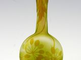 un vase vert orné de fleurs jaunes, posé sur un fond blanc
