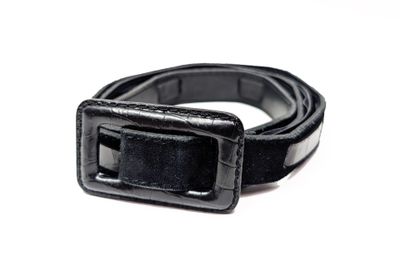 une ceinture noire avec une boucle métallique sur un fond blanc