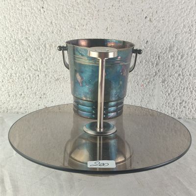 a silver ice bucket on a glass plate on a table