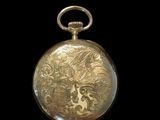 a gold pocket watch with a dragon design on it