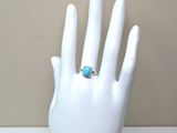une main portant une bague, posée sur un mannequin