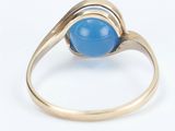 a close up of a gold ring with a blue stone