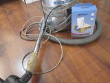 un aspirateur posé par terre à côté d'une boîte de papier toilette