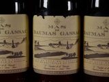 three bottles of wine are lined up on a shelf